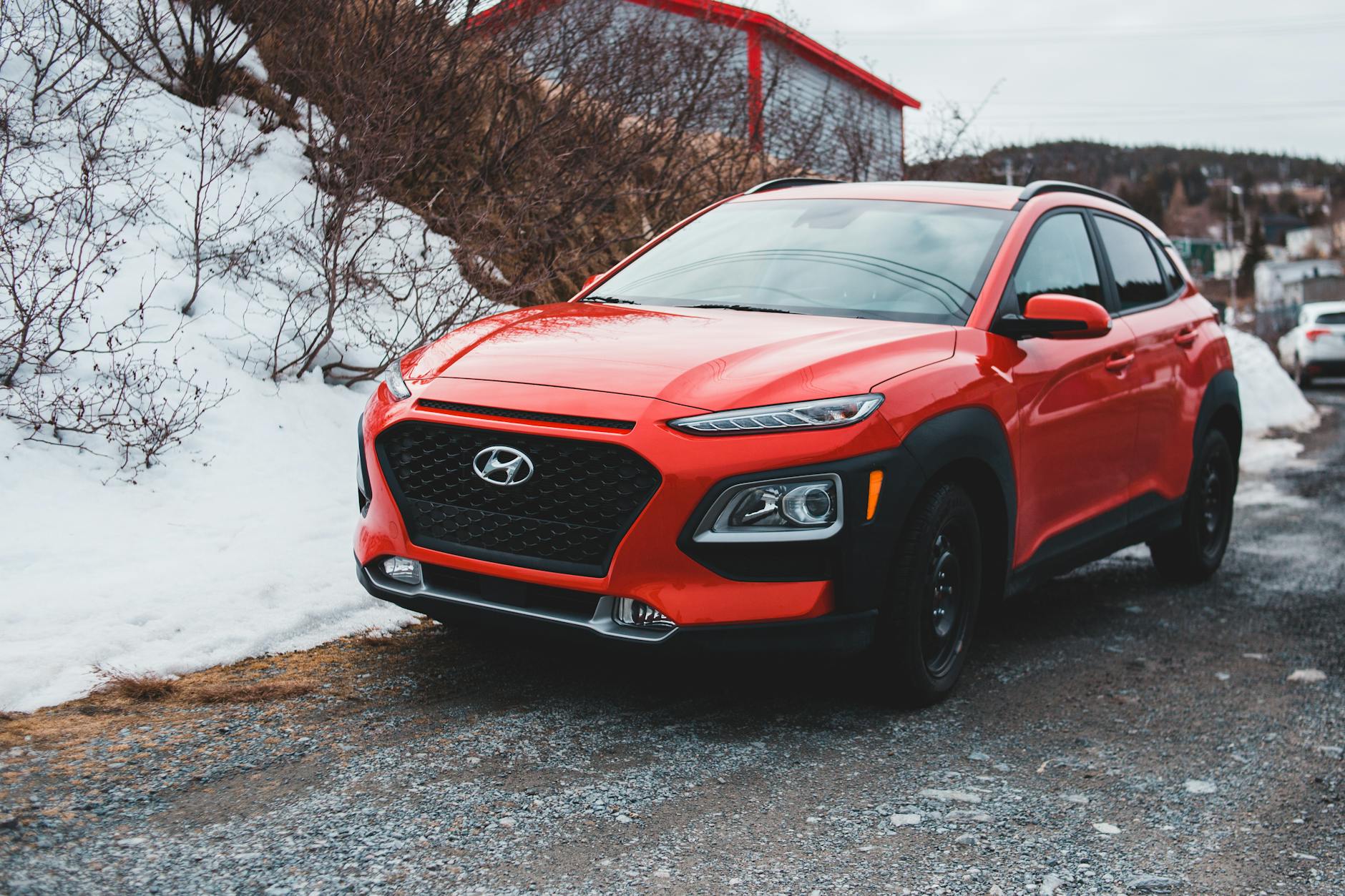 Hyundai Tucson czy Kia Sportage: który SUV lepiej sprawdzi się w codziennej jeździe Czerwony Hyundai SUV zaparkowany na śniegu przed artykułem o Tucson i Sportage