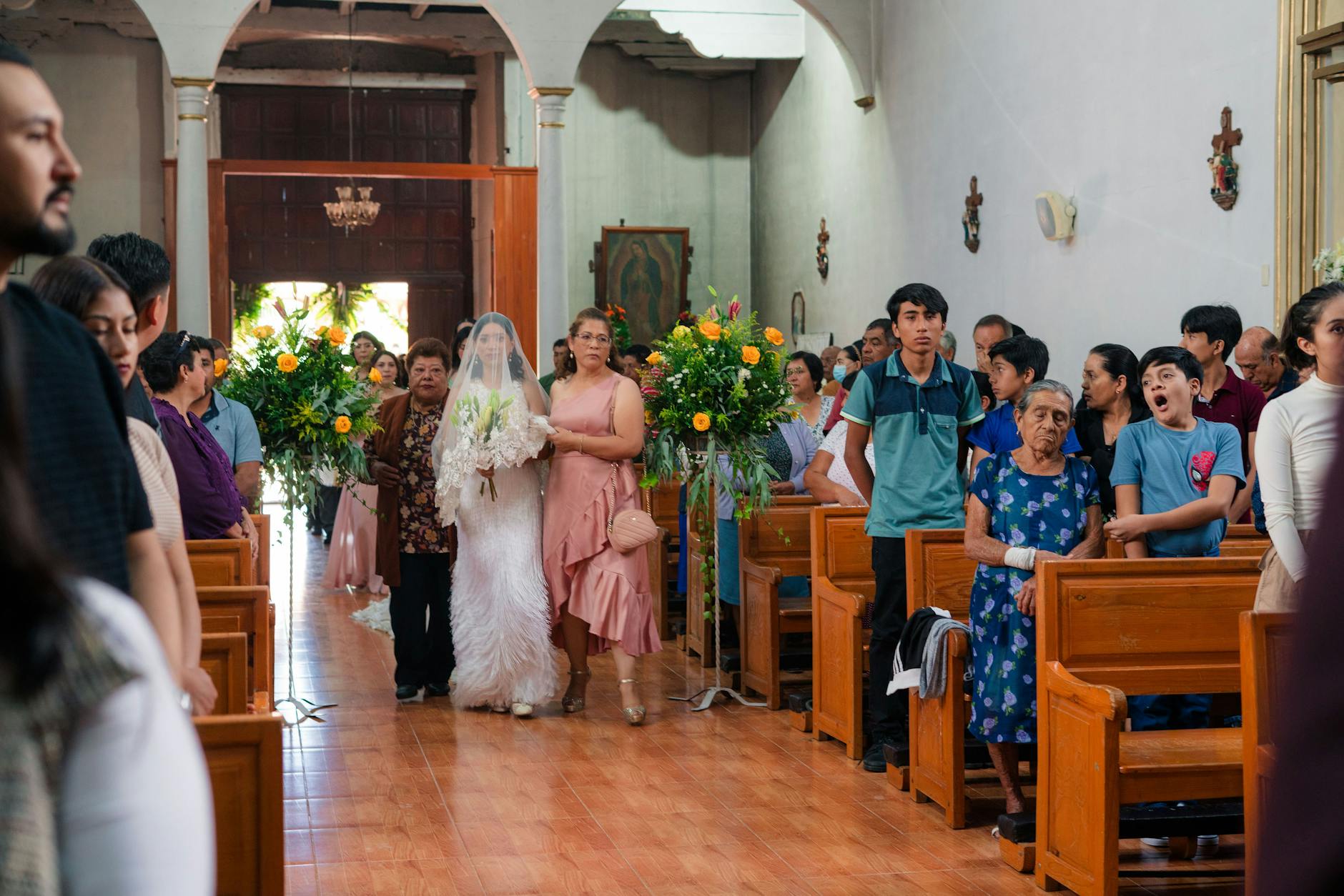 Panna młoda idzie do ołtarza z rodziną w udekorowanym kościele