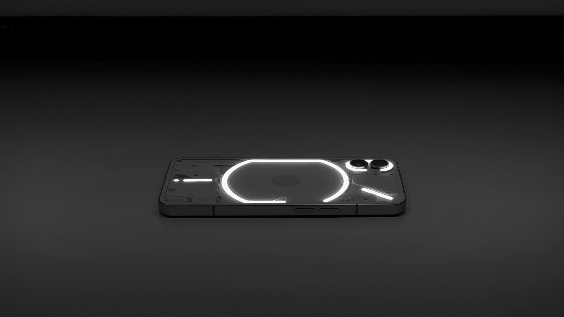Podświetlony smartfon z przezroczystym tyłem na ciemnym tle