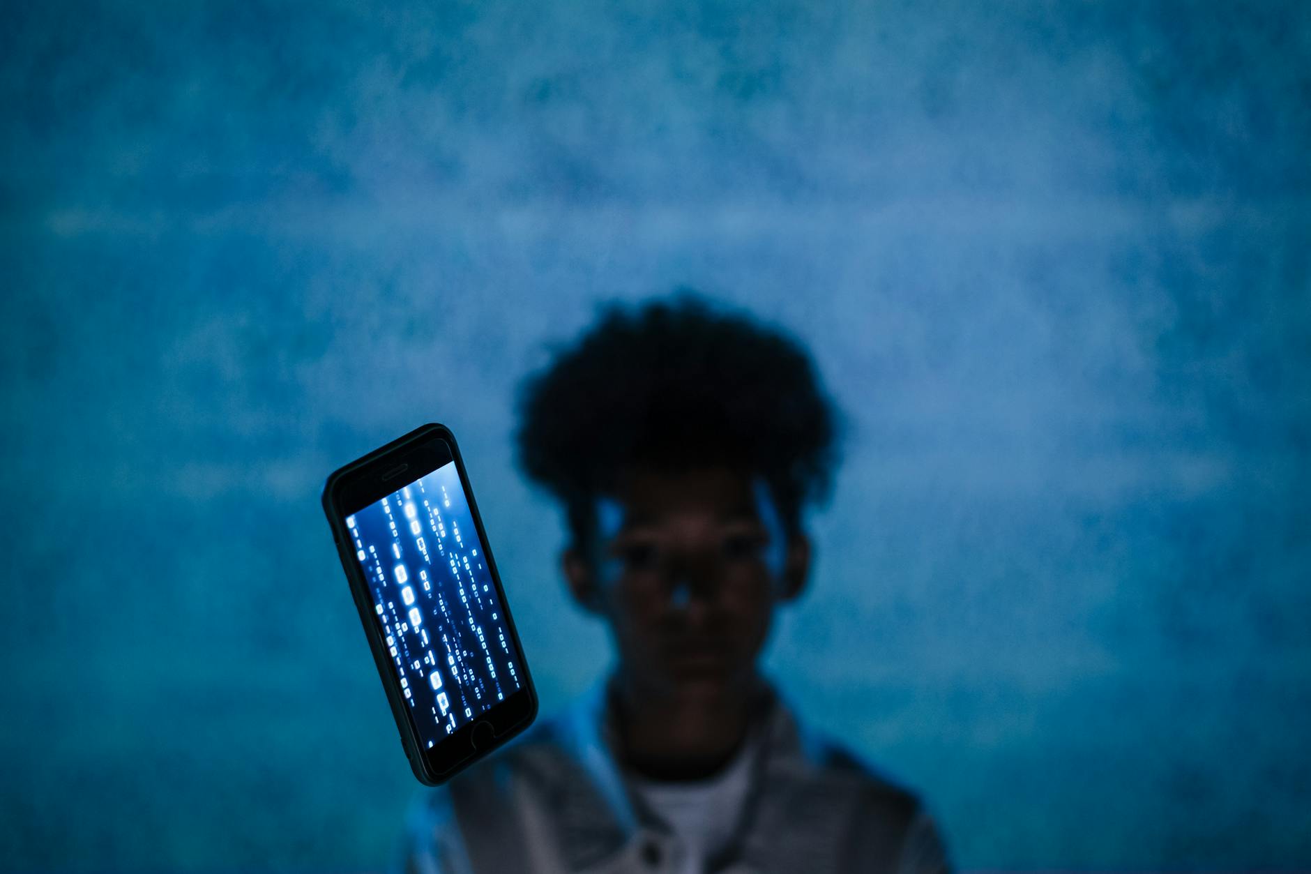 Smartfon z unoszącym się kodem cyfrowym na tle rozmytej postaci