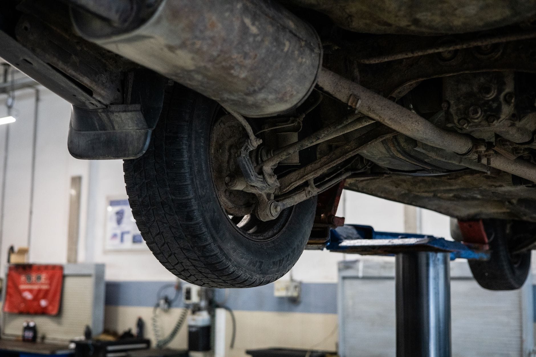 Mechanik ogląda zbliżenie podwozia auta na podnośniku w warsztacie Mechanik ogląda zbliżenie podwozia auta na podnośniku w warsztacie