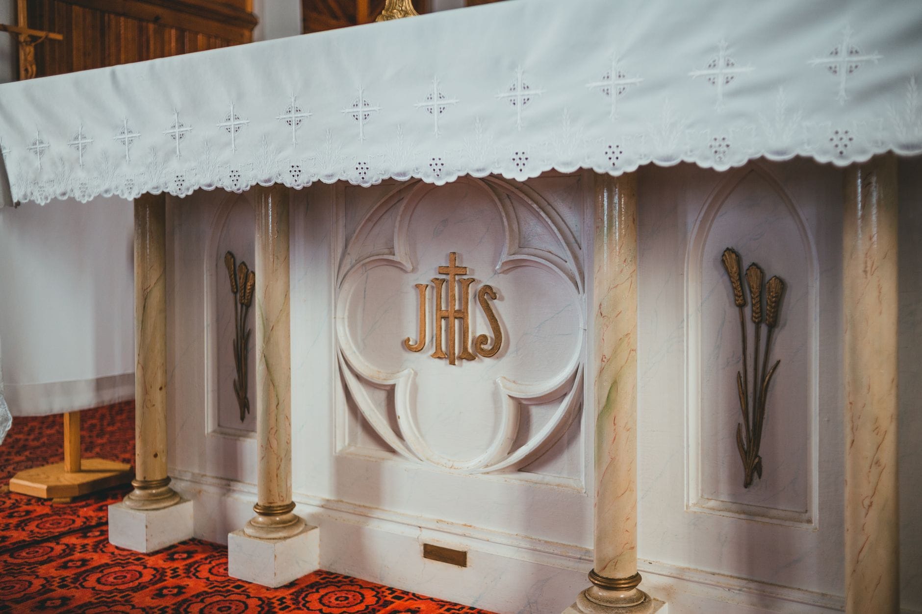 Ołtarz kościelny z symbolem IHS i złotymi, klasycznymi zdobieniami